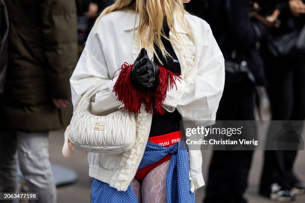 Monica Anoz wears white jacket, black shirt, bag, red micro shorts, black gloves with red fringes, blue button shirt wrapped around the hips outside...