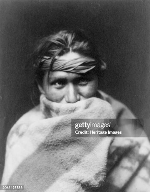 Son of the desert, circa 1904. Navajo man, head-and-shoulders portrait, facing front, wrapped in a blanket that covers his mouth. Creator: Edward...