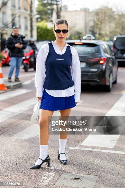 Catarina Pereira Nogueira wears blue top, white button shirt, bag, pleated mini skirt outside Lacoste during the Womenswear Fall/Winter 2024/2025 as...