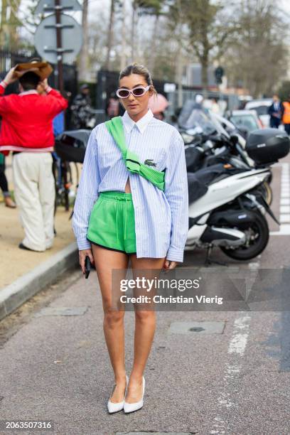 Mariana Machado wears blue white striped button shirt, green shorts. White heels outside Lacoste during the Womenswear Fall/Winter 2024/2025 as part...