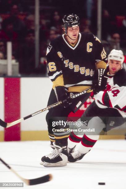 Pittsburgh Penguins forward, Mario Lemieux, rushes towards a loose puck with Devil's forward, Stephane Richer, just behind him during the game...