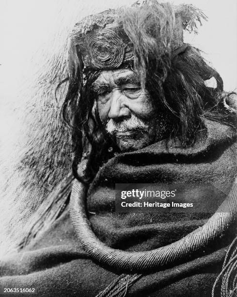 The Hamatsa-Nakoaktok circa 1910. Half-length portrait of Nakoaktok man, facing left, wearing cedar root ceremonial loop. Creator: Edward Sheriff...