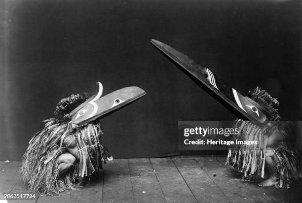 Kotsuis and Hohhug-Nakoaktok, wearing ceremonial dress, with long beaks, on their haunches, dancing, circa 1914. Creator: Edward Sheriff Curtis.