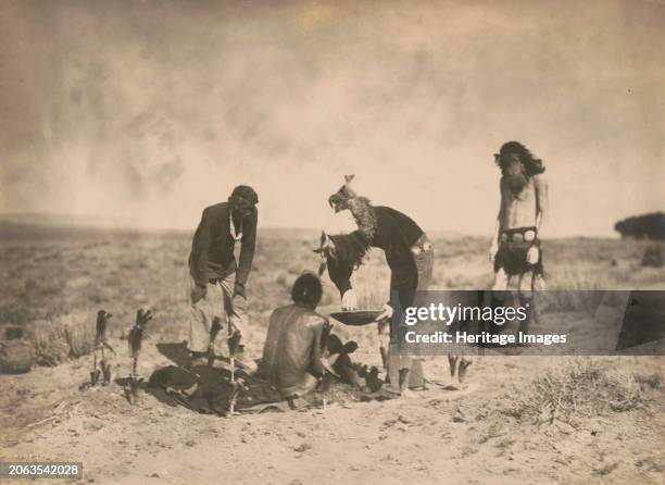 Giving the medicine-Navaho, circa 1905. Photograph shows aNavajo shaman giving medicine to participant sitting atop blanket used in sweatbath, as two...