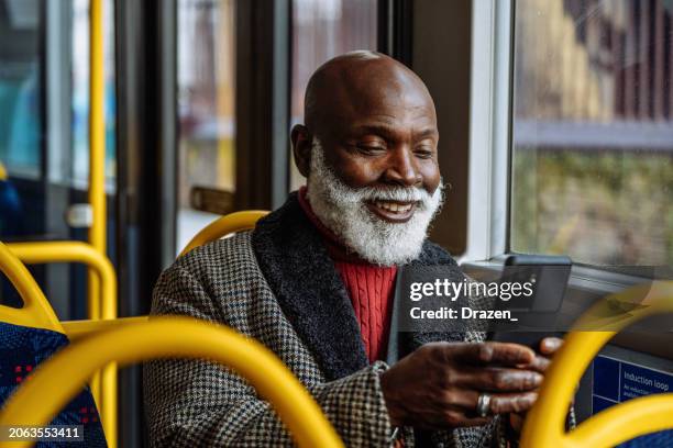 senior african man using public transport and text messaging on smart phone device - old man smart stock pictures, royalty-free photos & images