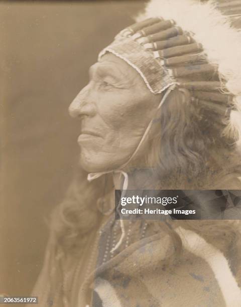 Red Shirt, 1905. Photograph shows Red Shirt, wearing headdress and blanket, head-and-shoulders portrait, profile facing left. Creator: Edward Sheriff...