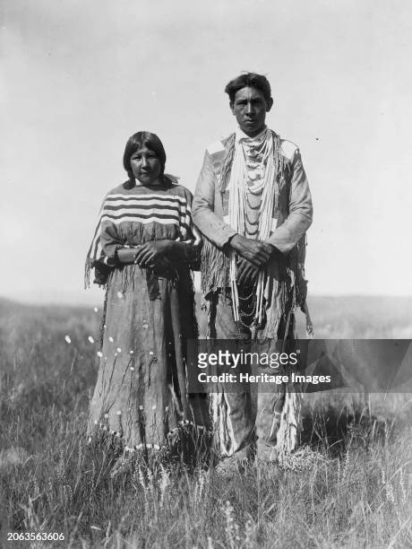 Joe Russell, circa 1910. Piegan man and woman standing in open prairie. Creator: Edward Sheriff Curtis.