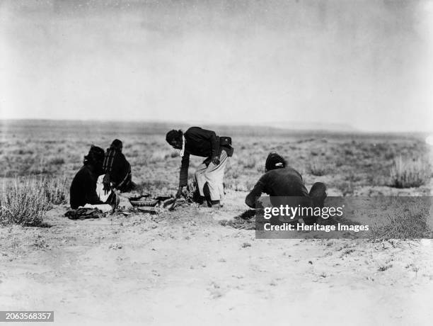 Preparing the sweat, circa 1905. Four Navajo Indians preparing hot embers, covering them with brush and weeds on second day of Yebichai ceremony....