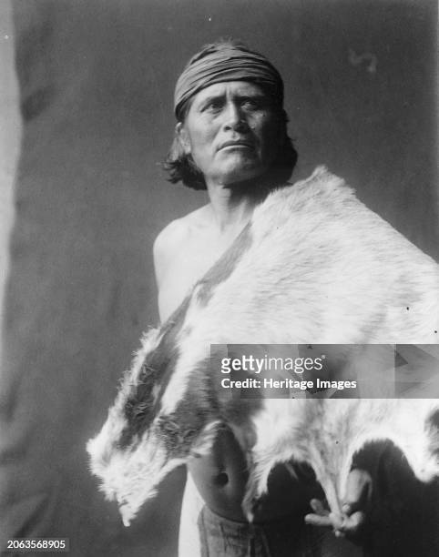 Nato, the goat man-Hopi, circa 1906. Half-length portrait of Hopi man with animal skin. Creator: Edward Sheriff Curtis.