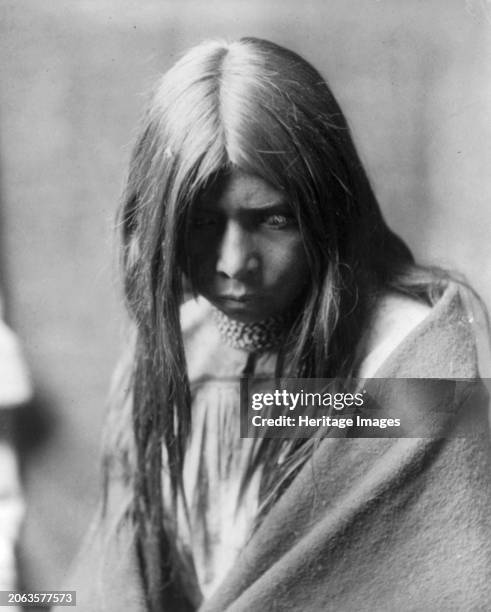 Zosh Clishn-Apache, circa 1906. Zosh Clishn, half-length portrait, facing front, looking down, wrapped in a blanket and wearing several necklaces....