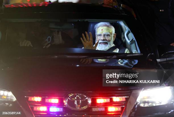 India's Prime Minister Narendra Modi waves to supporters from a car after offering prayers at the Kashi Vishwanath Hindu temple in Varanasi on March...