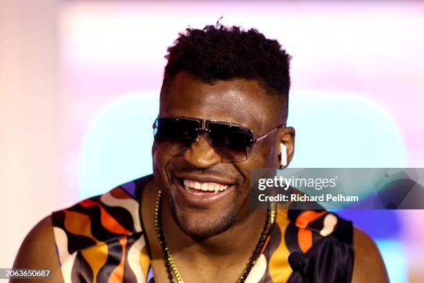 Francis Ngannou reacts as he wears the Apple AirPods of Anthony Joshua at the press conference ahead of his 'Knockout Chaos' heavyweight fight...