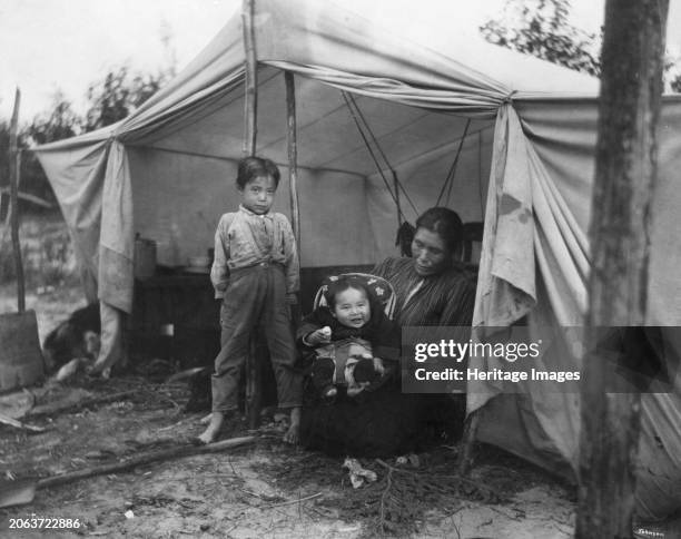 Indian children and mother at entrance of tent, between circa 1900 and 1927. Creator: Unknown.