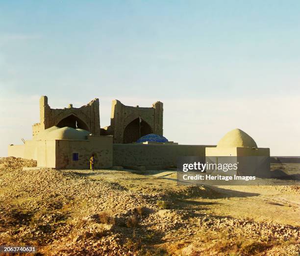 Walled adobe structure with domes and arches in desert area, with man posed in front for scale, [Central Asia?], between 1905 and 1915. Russian...