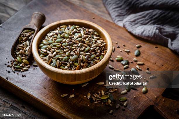 mezcla de semillas de girasol y calabaza tostadas en un bol de madera - semilla-de-lino fotografías e imágenes de stock