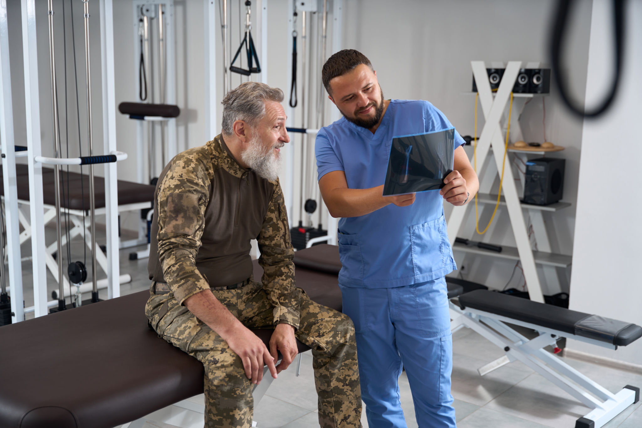 Physiotherapist with a patient in military clothing examines x-rays Physiotherapist with a patient in military clothing examines x-rays