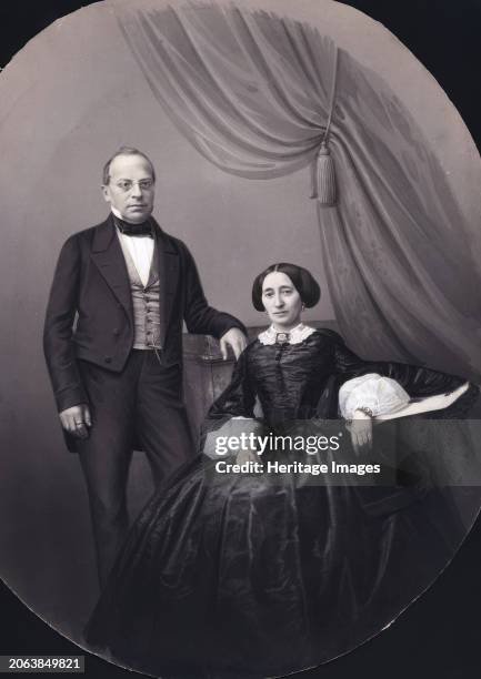 Full-length cabinet portrait, 1860-1865. A man and a woman, the woman seated, in a costume that suggests circa 1860. Both wear a plain ring on the...