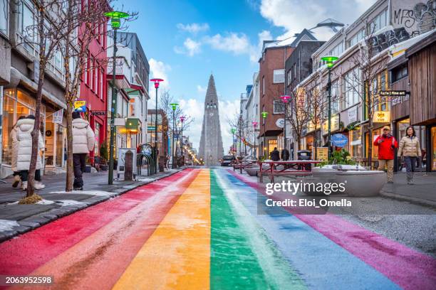 people walking on the rainbow painted skolavordustigur street - reykjavik street stock pictures, royalty-free photos & images