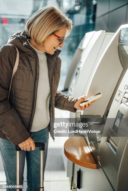 woman using phone to buy a ticket at the train station - gepäckautomaten stock-fotos und bilder