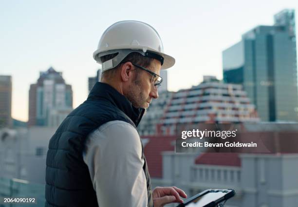 man, engineer and tablet with helmet in city for industrial design, architecture or research. male person, contractor or architect with hard hat and technology on balcony or rooftop for construction - handyman stock pictures, royalty-free photos & images