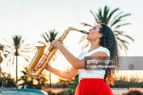 passionate woman playing saxophone at skate park - saxophoniste photos et images de collection