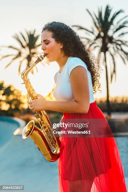 woman with curly hair practicing saxophone at skate park - instrument à bec photos et images de collection