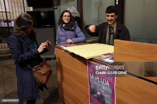 Sign reads in Catalan "Rogation for rain" as a woman buys a candle at the Santa Maria del Pi basilica prior to participating in a procession to pray...