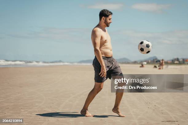 man kicking soccer ball on the beach - kicking sand stock pictures, royalty-free photos & images