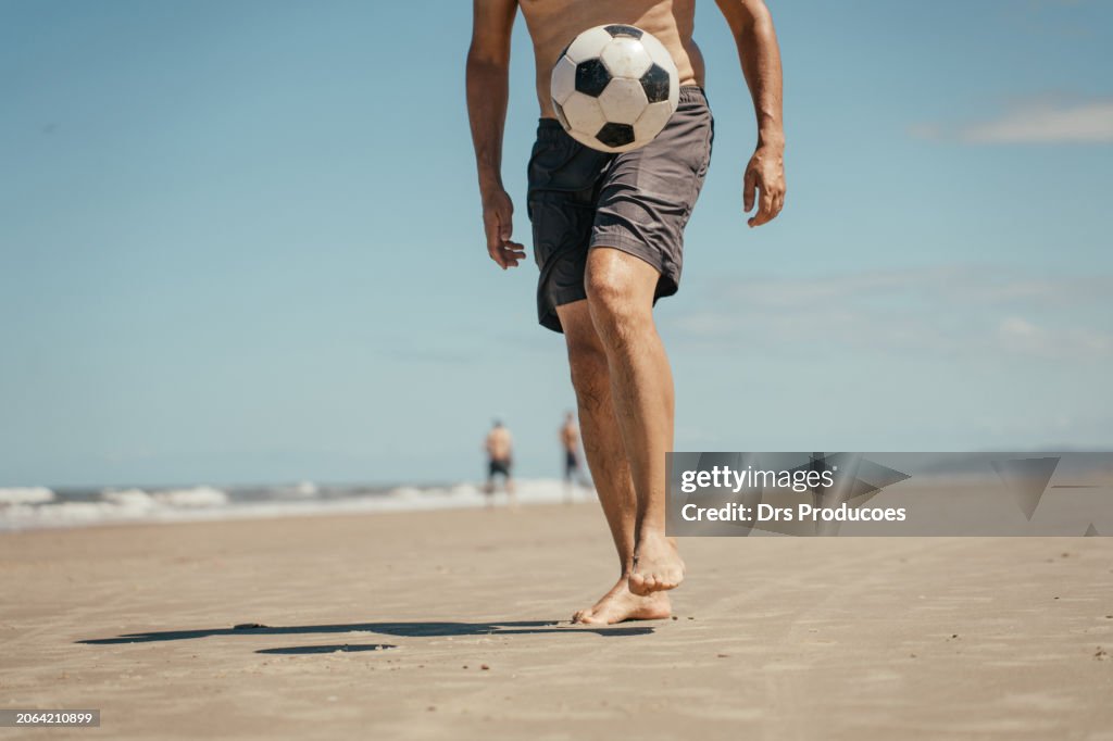 Man kicking soccer ball on the beach