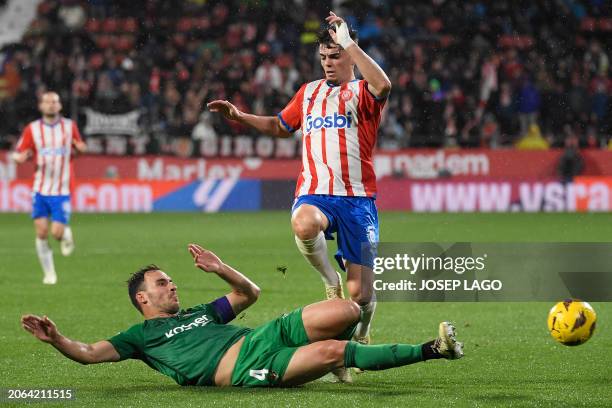 Osasuna's Spanish defender Unai Garcia tackles Girona's Spanish defender Miguel Gutierrez during the Spanish league football match between Girona FC...