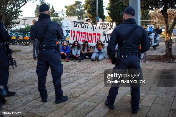 Activists stands with their hands duct taped together, duct tape over her mouth, and their hands dyed the color of blood, as they protest for the...