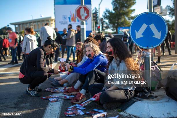 Activists sit with their hands duct taped together, duct tape over her mouth, and their hands dyed the color of blood, as they protest for the return...