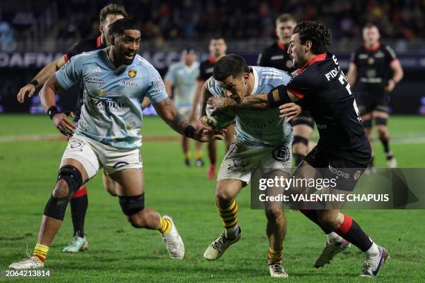 Perpignan's Italian full-back Tommaso Allan is tackled by Toulouse's French centre Baptiste Germain during the French Top14 rugby union match between...