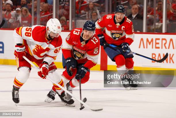 Sam Reinhart of the Florida Panthers battles for possession against Oliver Kylington of the Calgary Flames at the Amerant Bank Arena on March 9, 2024...