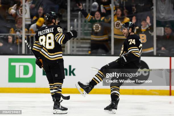 Jake DeBrusk of the Boston Bruins moves in to congratulate David Pastrnak after he scored his 40th goal of the year during the second period against...