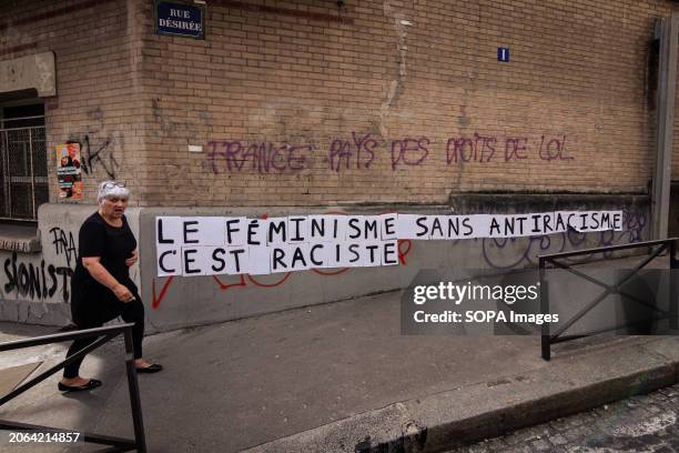 An old lady passes in front of a feminist message stuck on a wall, "Feminism without anti-racism is racism" is seen on the wall, during the...