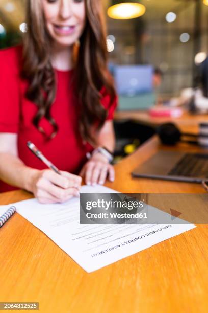 mature businesswoman signing contract at desk in office - legal documents stock pictures, royalty-free photos & images