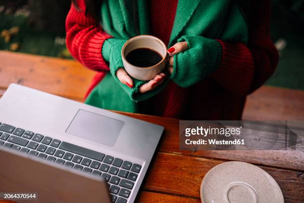 freelancer holding coffee cup near laptop in cafe - fingerless glove stock pictures, royalty-free photos & images