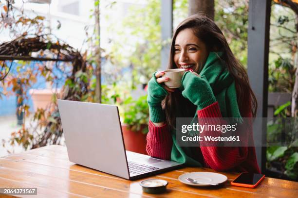 happy freelancer sitting with coffee cup in cafe - fingerless glove stock pictures, royalty-free photos & images