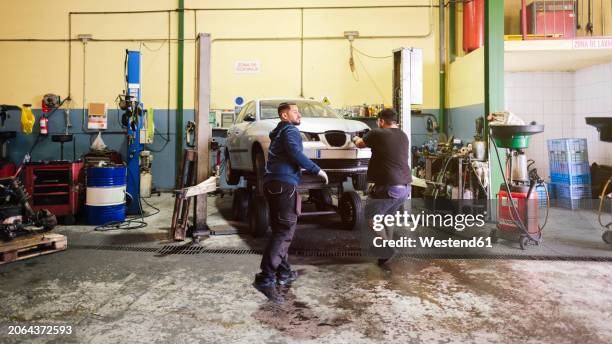 mechanics working near car at workshop - dismantling stock pictures, royalty-free photos & images