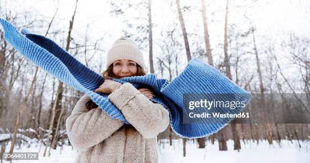 young woman with blue scarf standing in winter forest - woman flying scarf stock pictures, royalty-free photos & images