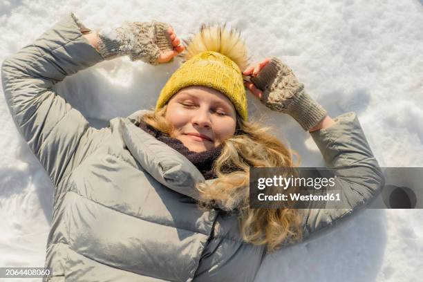 smiling woman lying on snow with eyes closed - luva sem dedos imagens e fotografias de stock