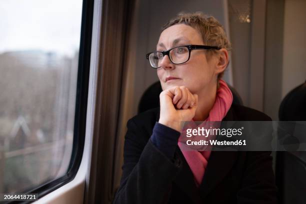 thoughtful businesswoman wearing eyeglasses and traveling in train - older woman colored hair stock pictures, royalty-free photos & images