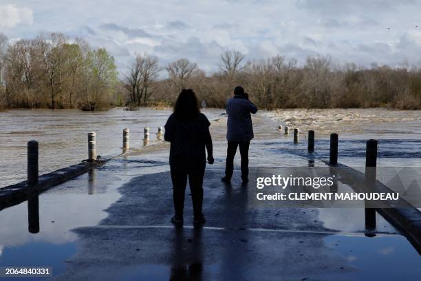 Man takes a picture of a bridge submerged by the flooded Gard river in Dions, on March 10, 2024 following heavy rain over south-eastern France.