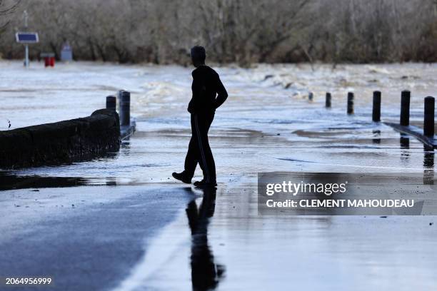 Man walks by a bridge submerged by the flooded Gard river in Dions, on March 10, 2024 following heavy rain over south-eastern France.