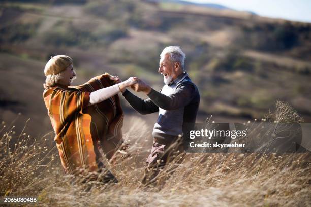 cheerful senior couple having fun in autumn day on a hill. - paartanz stock-fotos und bilder