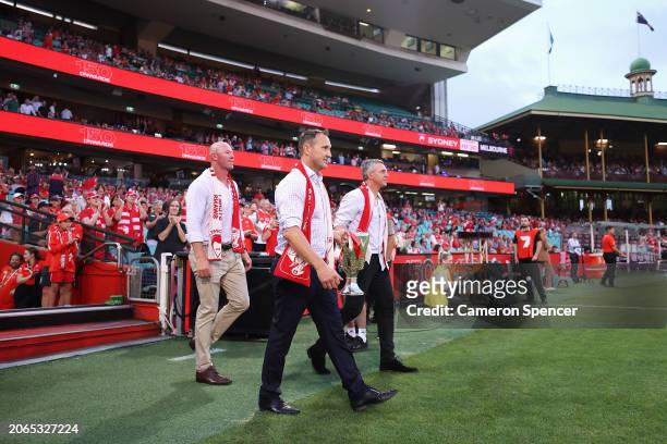 Former Swans players Barry Hall, Jude Bolton and Leo Barry walk onto the field with a Premiership Cup during the Opening Round AFL match between...