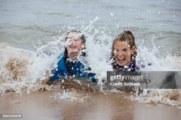 silly moments in the sea - mother and daughter lying on beach stock pictures, royalty-free photos & images