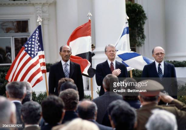 Egyptian President Anwar Sadat , US President Jimmy Carter and Israeli Prime Minister Menachem Begin listen to the national anthems before signing...