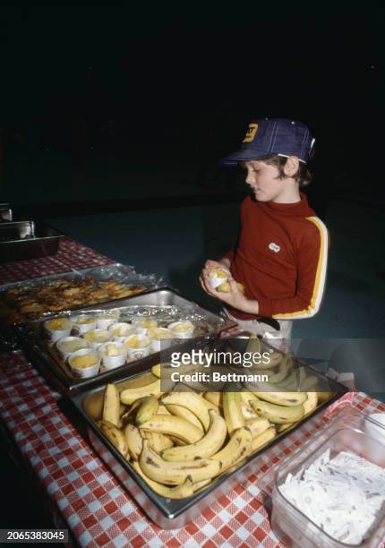 Boy picking up food at a mass care centre set up for evacuees at the Hershey Park Arena, Pennsylvania, March 31st 1979. People were evacuated to...
